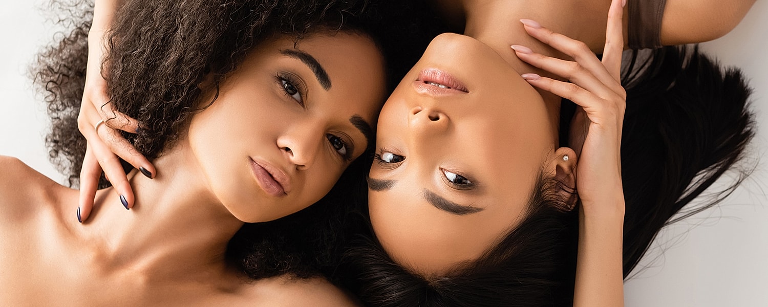 Two women lying closely together, sharing affection.