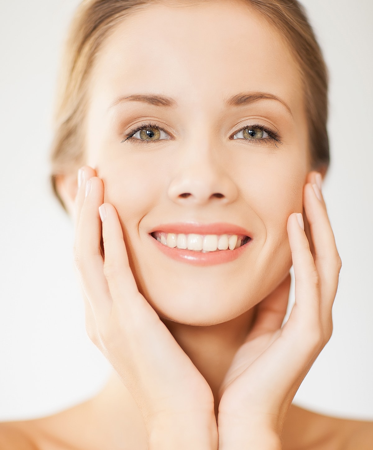 Smiling woman touching her face gently.