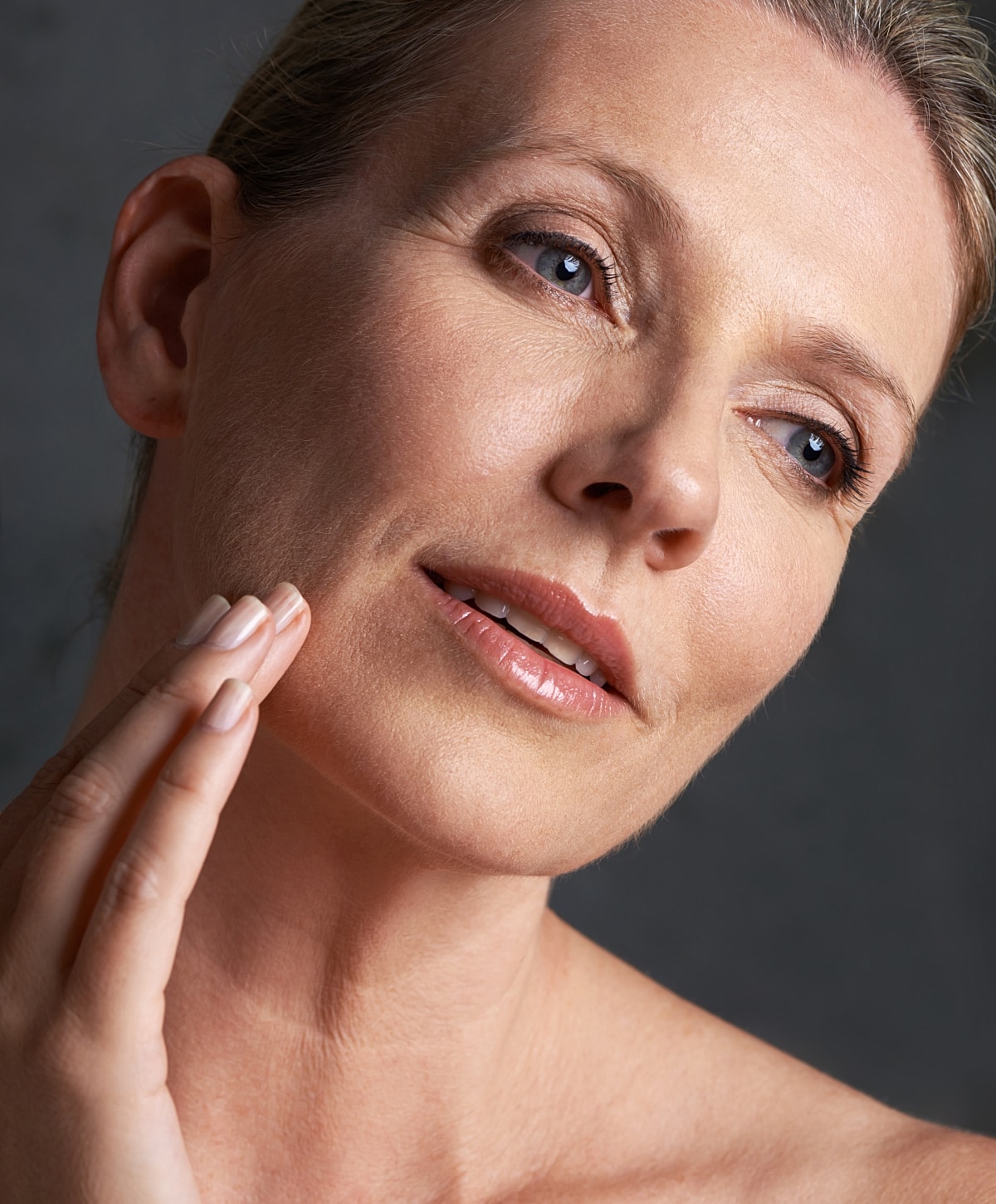 Woman gently touching her face, soft expression.