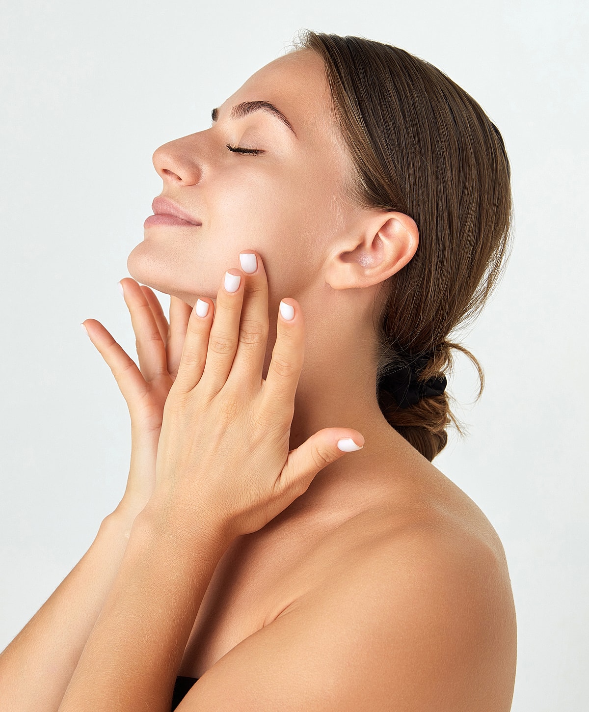 Woman enjoying skincare routine, hands on face.