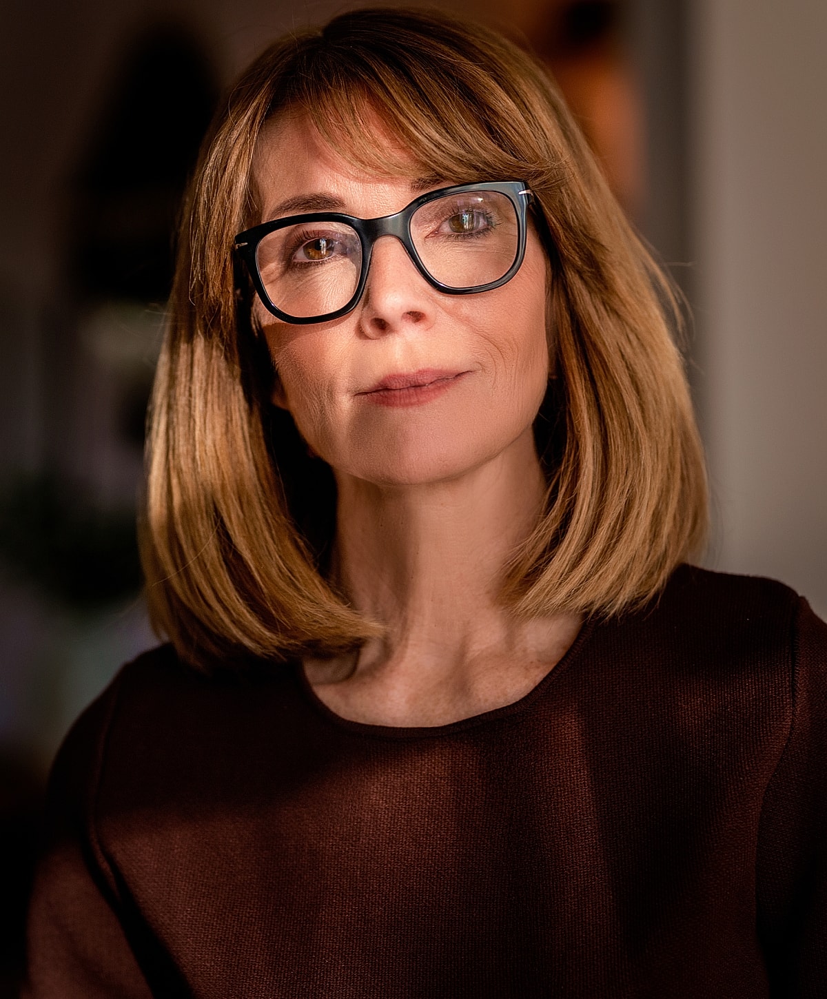 Woman with glasses in soft lighting portrait.