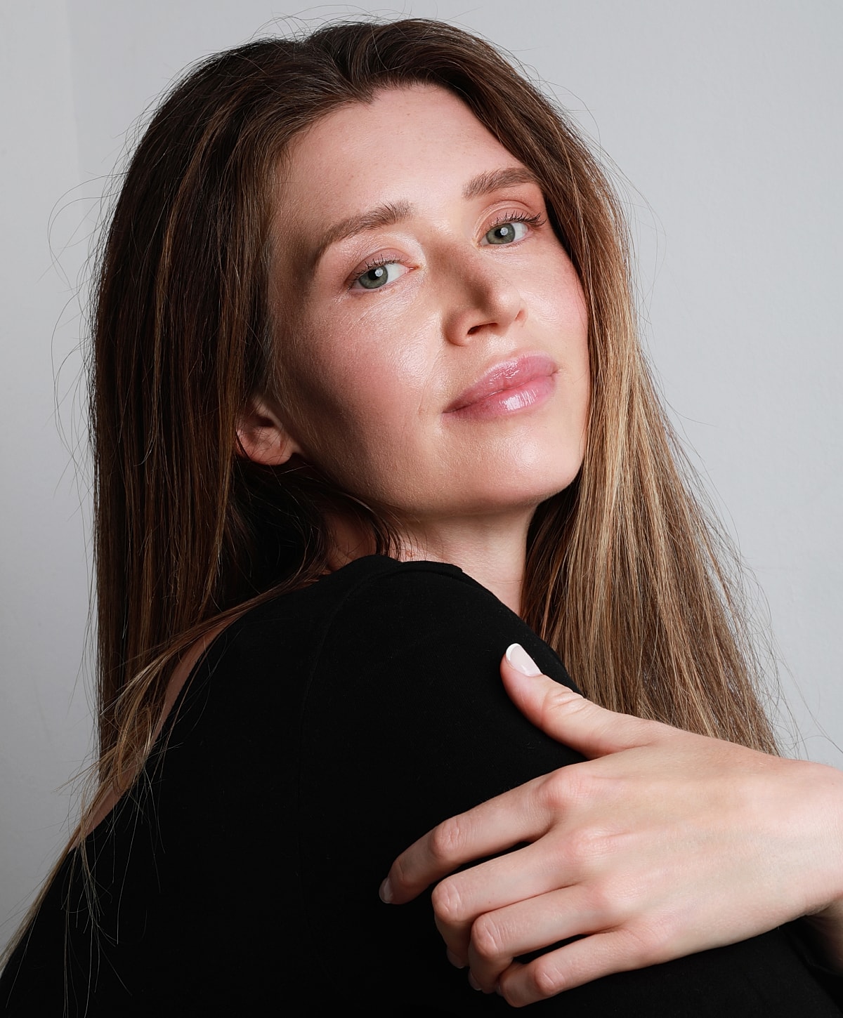 Woman with long hair posing against white background.