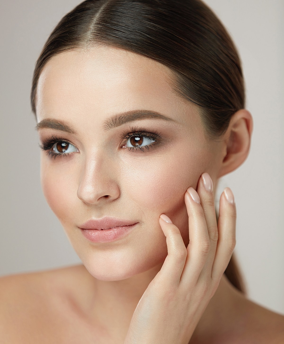 Close-up of a woman touching her face.