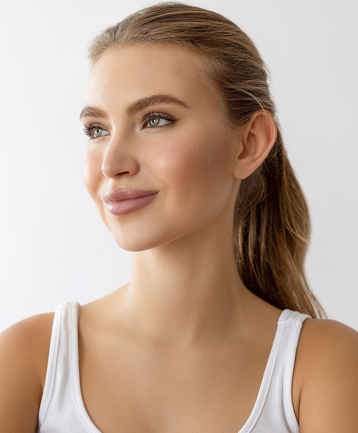 Smiling woman with natural makeup and ponytail.