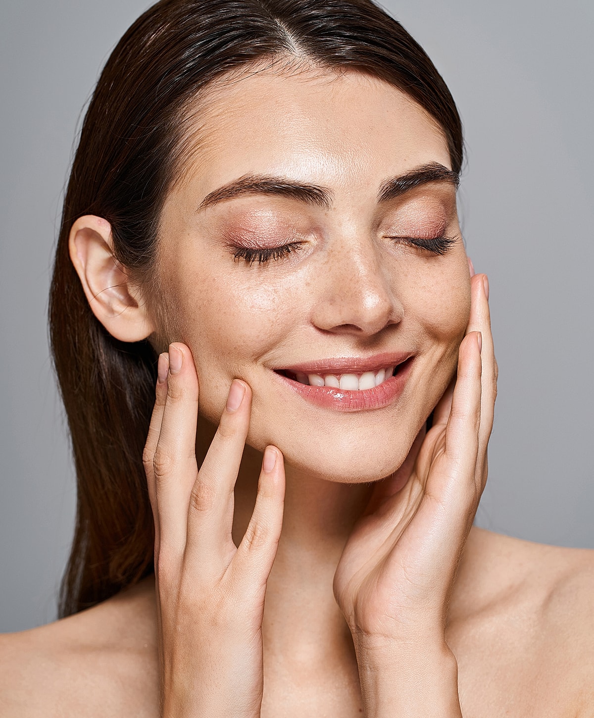 Smiling woman touching her face with hands.