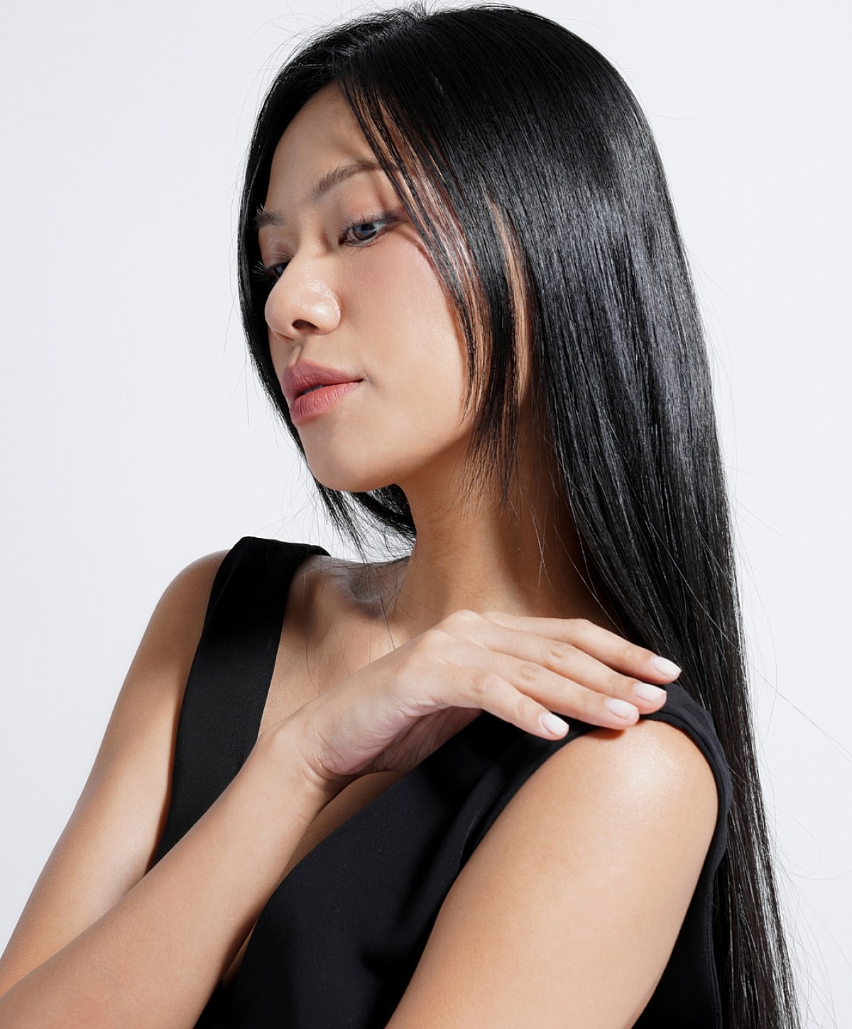 Woman in black dress, profile view, touching shoulder.