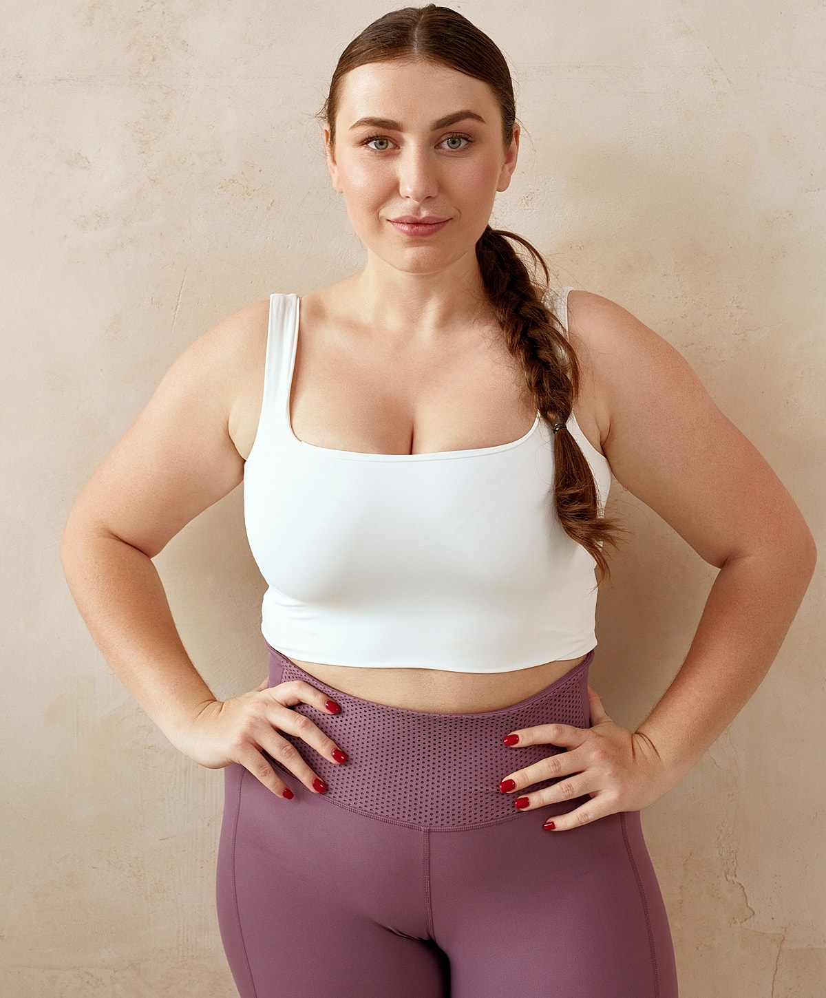 Woman posing in athletic outfit against neutral background.