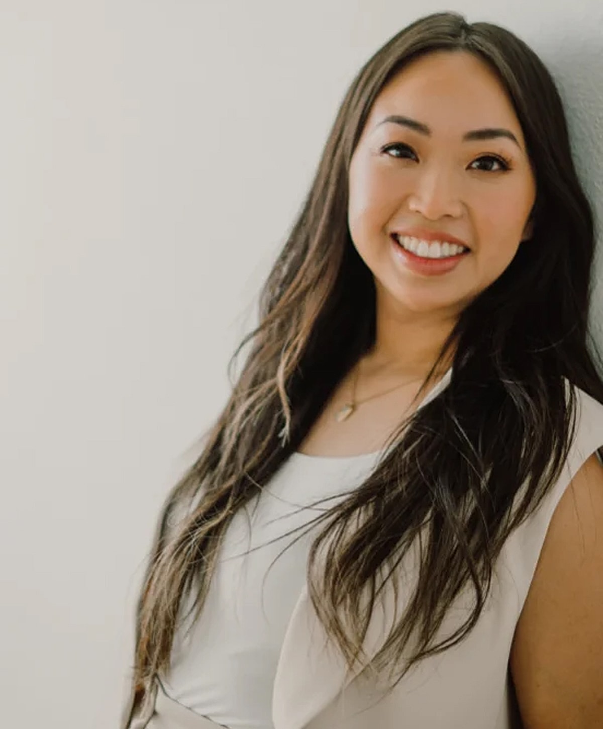 Smiling woman with long hair leaning against wall