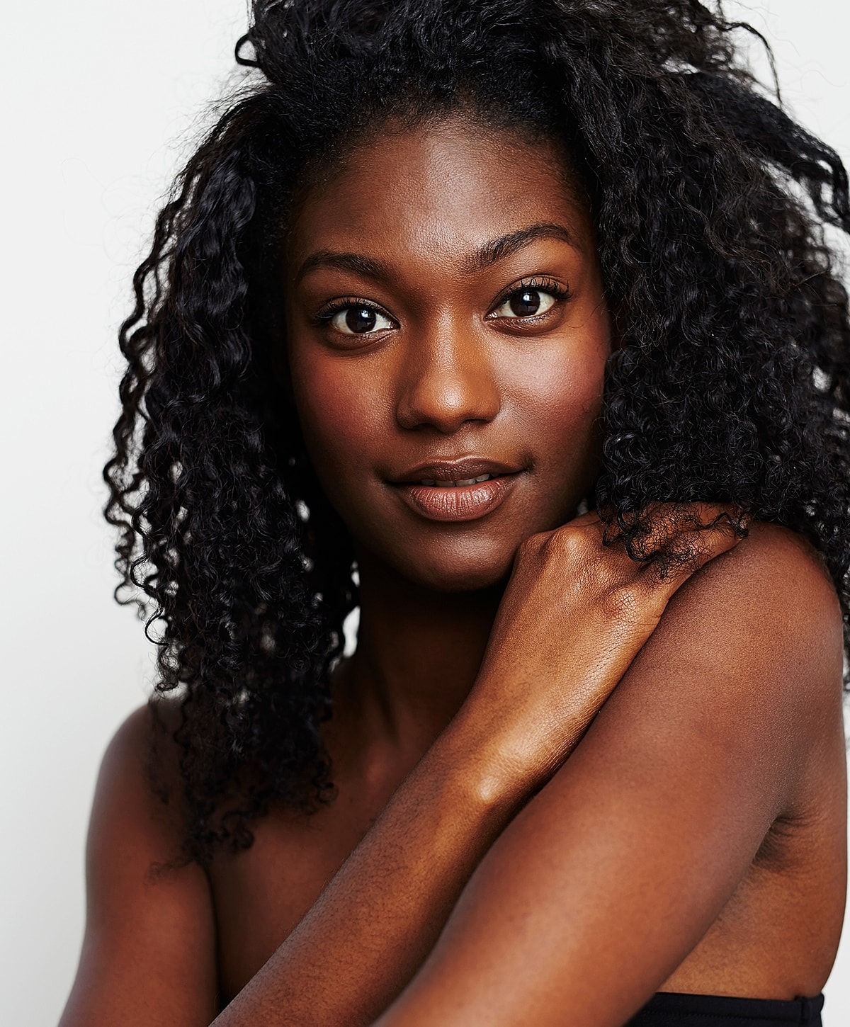 Woman with curly hair smiling confidently at camera.