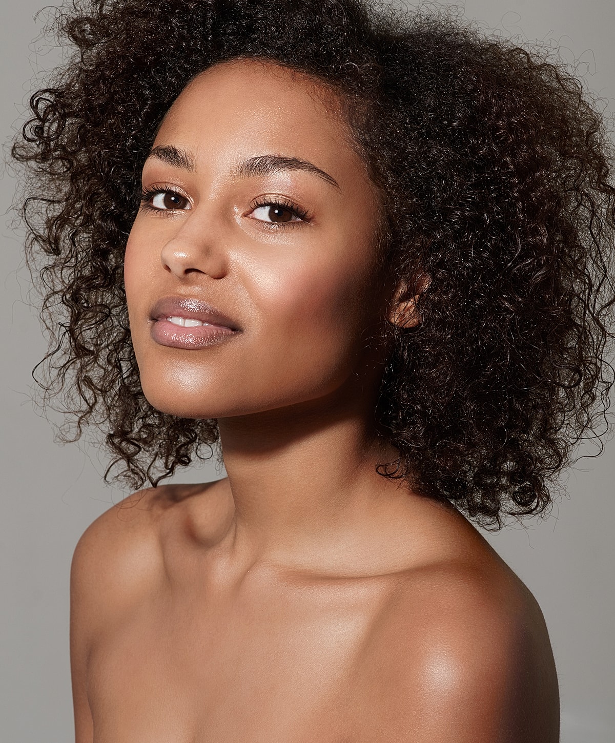 Smiling woman with curly hair and natural makeup.