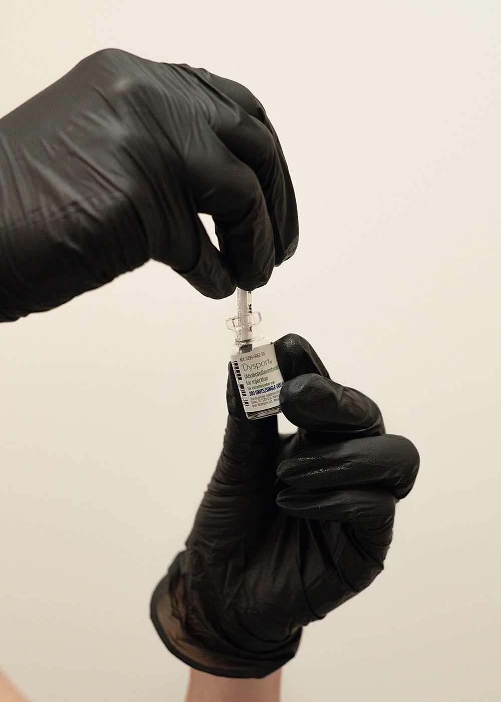 Hand holding a vial and syringe preparation.