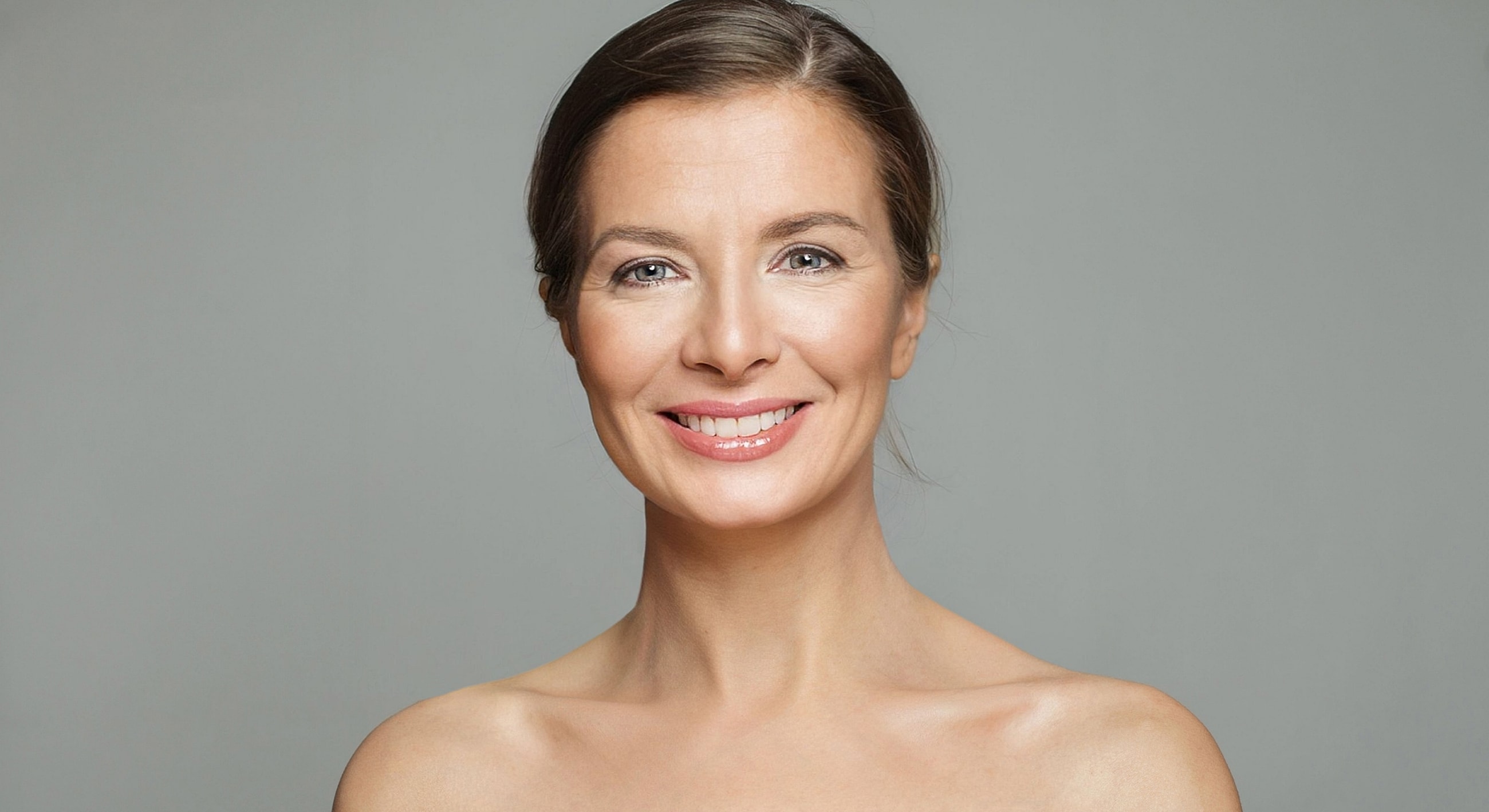 Smiling woman with natural makeup against gray background