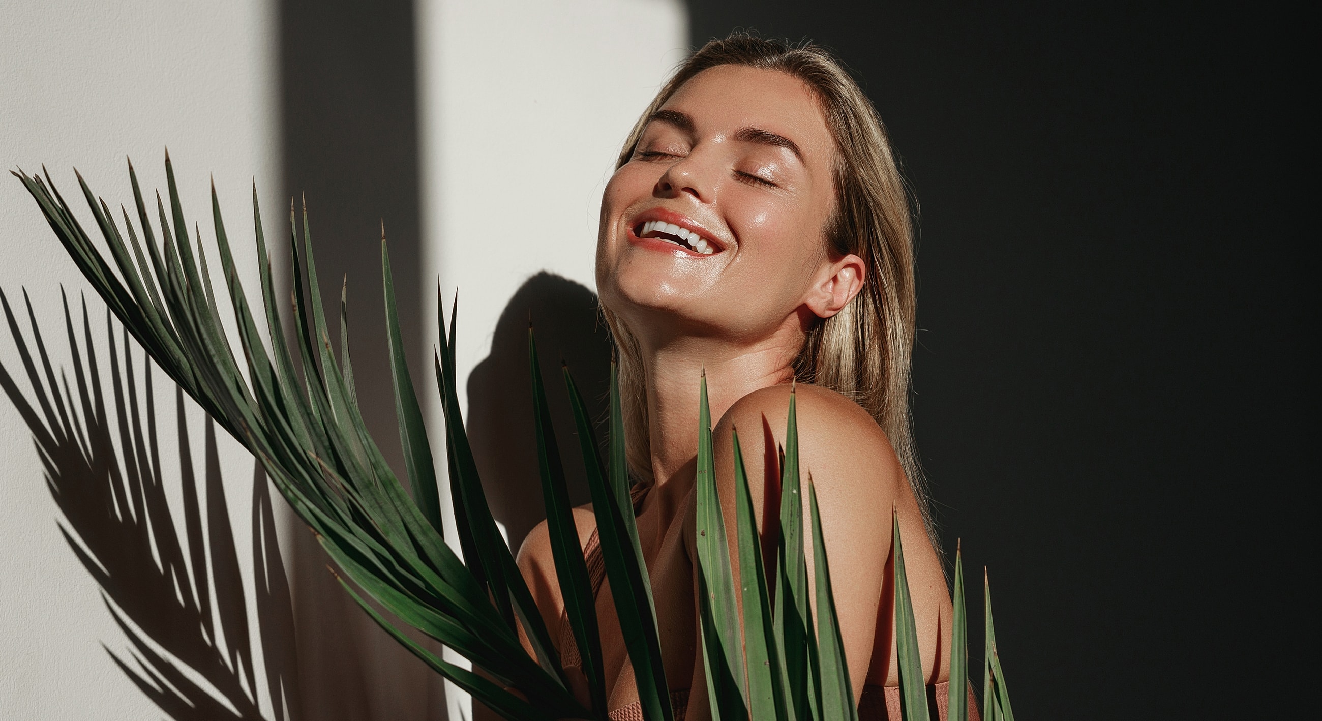 Smiling person with palm leaves in sunlight.