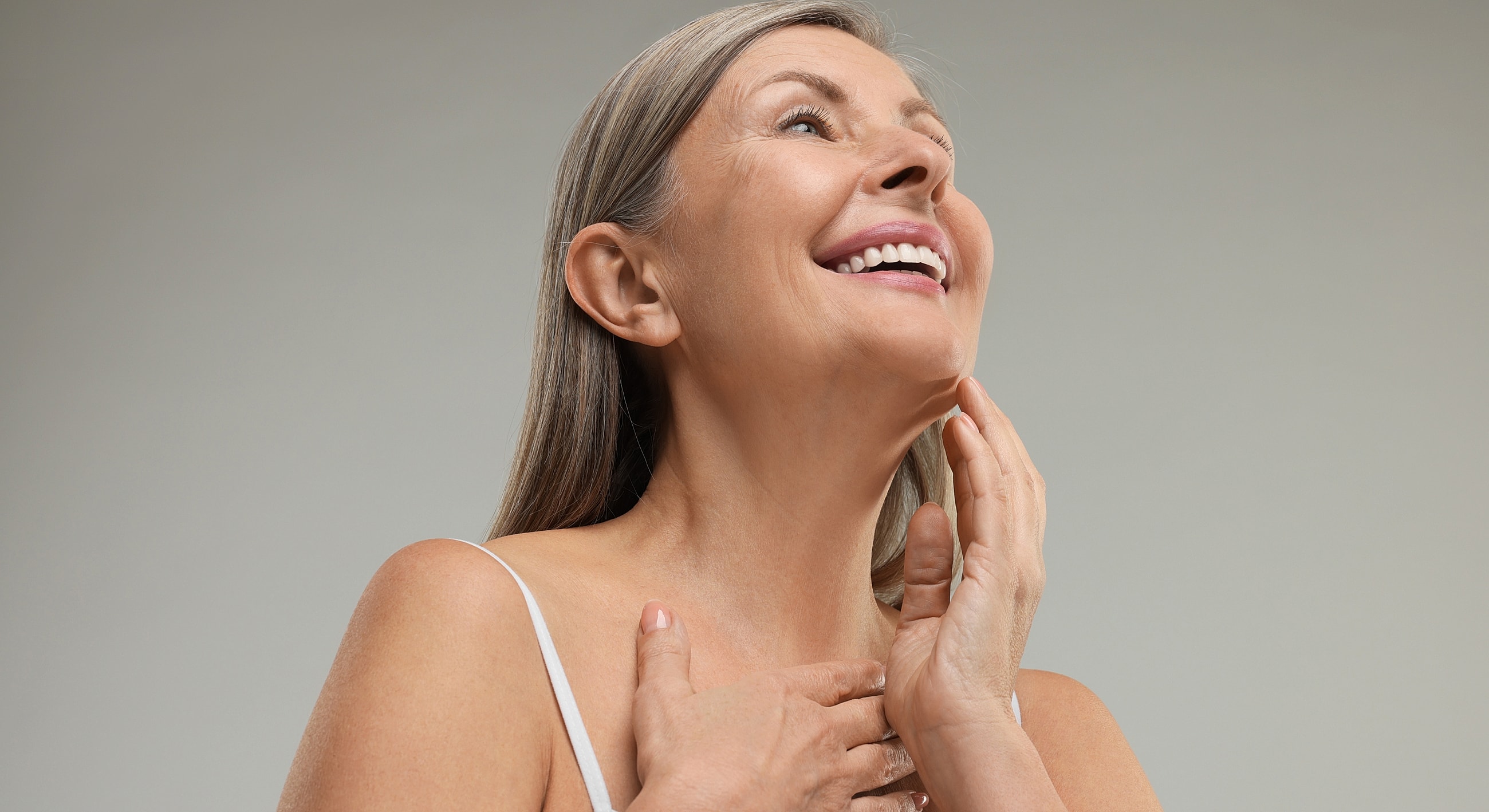 Smiling woman touching her neck and chin.