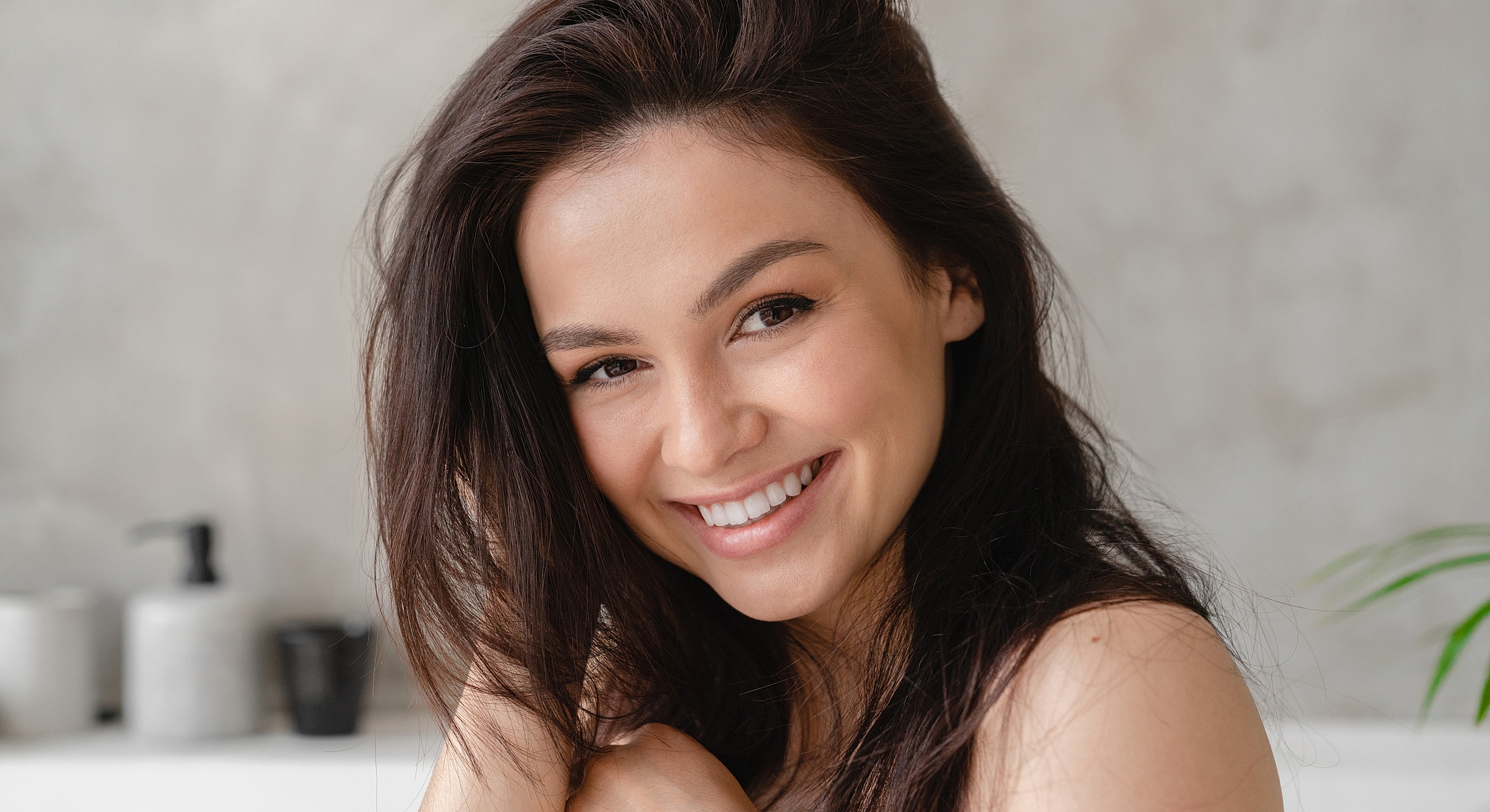 Smiling woman with long dark hair indoors.
