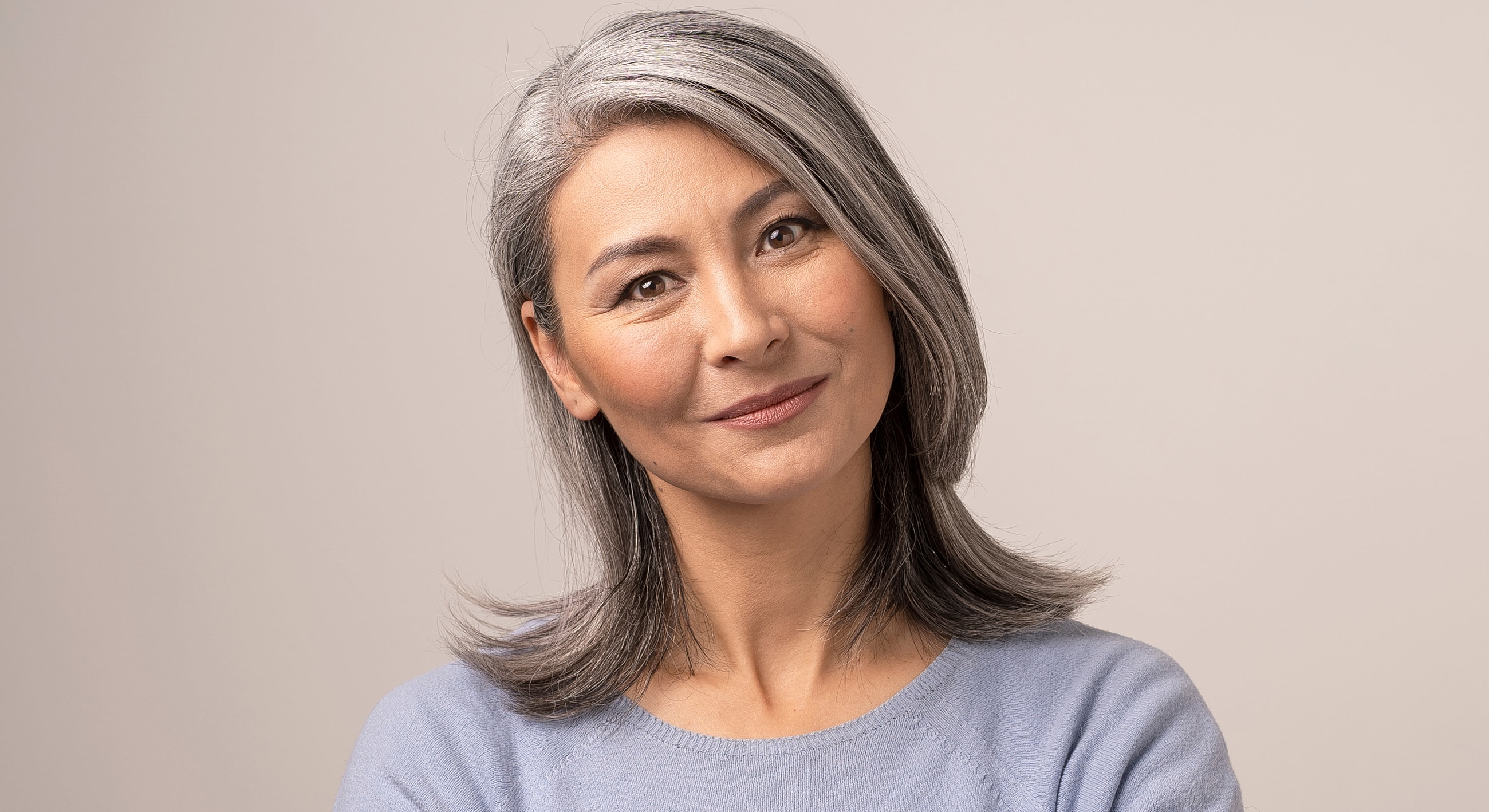 Smiling woman with gray hair and light sweater.
