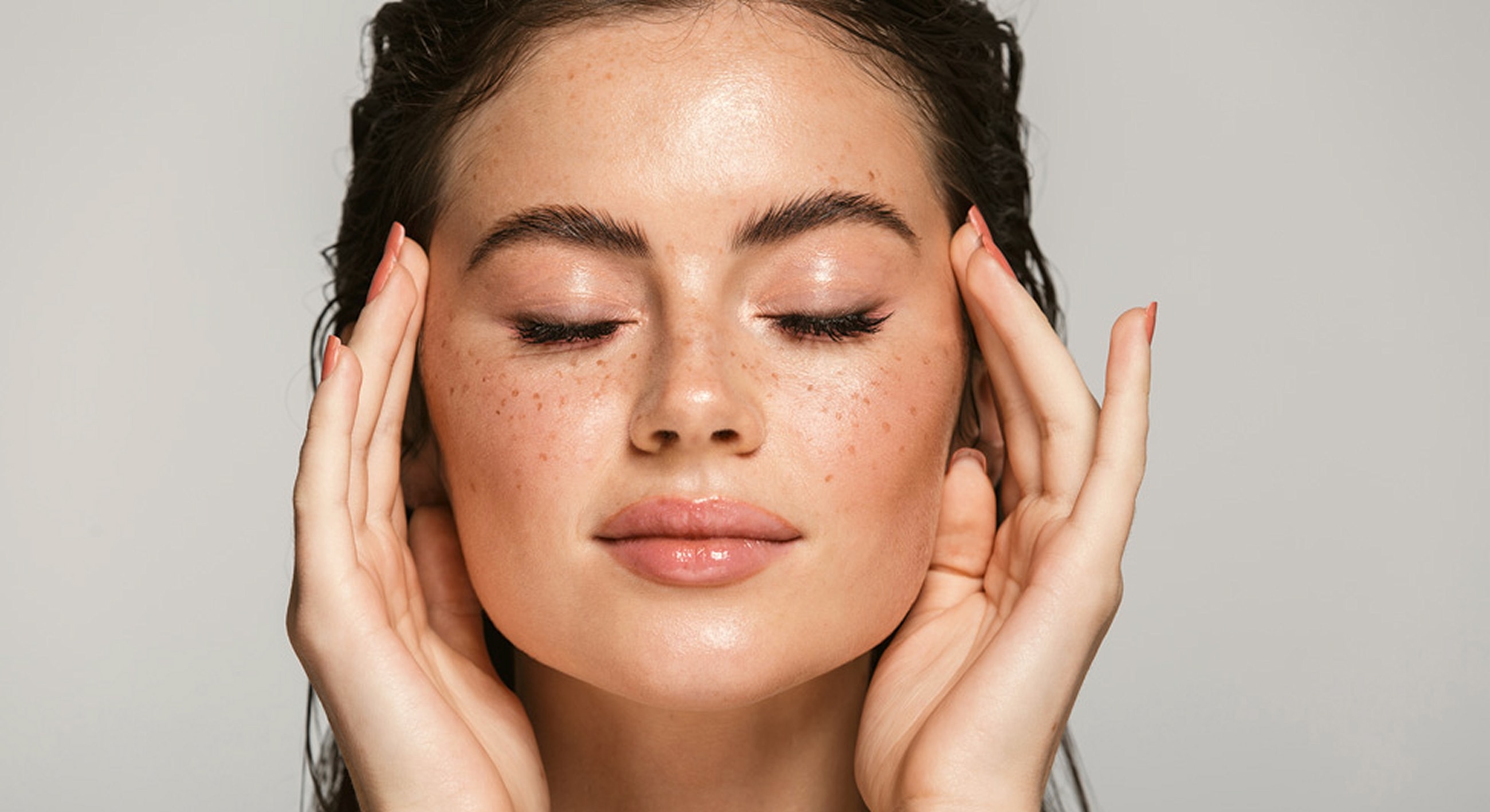 Woman with closed eyes relaxing and touching face.